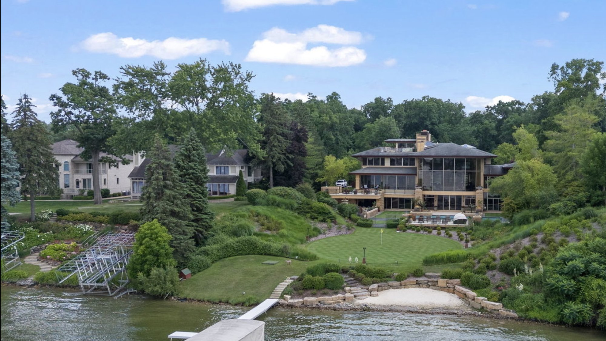 Landscaped backyard of a large home — pool, terraces, and lawn by the water